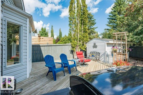 Expansive wood deck with a built-in shed and privacy fencing, surrounded by mature trees - 4705 43 Street, Beaumont, AB 