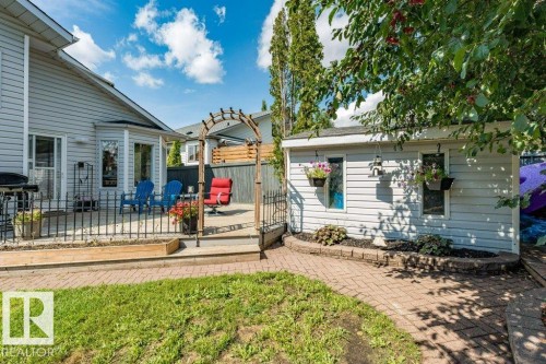 Outdoor patio with a black metal railing and a wood arbor entry - 4705 43 Street, Beaumont, AB 