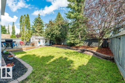 Expansive backyard featuring a fenced perimeter, mature trees, a raised garden bed, and a detached shed - 4705 43 Street, Beaumont, AB 