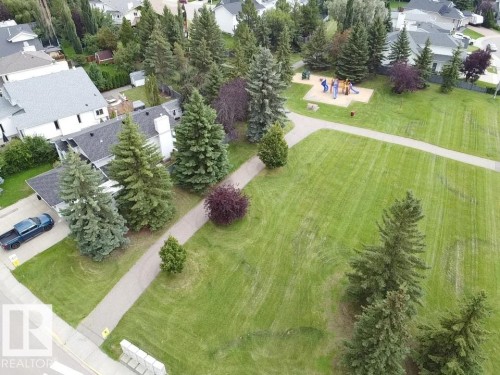 Expansive green space featuring a playground, paved walking paths, and mature trees - 4705 43 Street, Beaumont, AB 