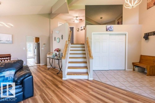 Vaulted ceiling, wood-finish flooring, ceramic tile flooring, staircase with wood handrails, and bi-fold closet doors - 4705 43 Street, Beaumont, AB 