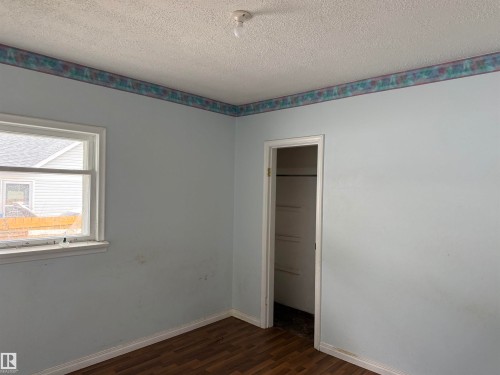 Wood-finish flooring, a single window, and an open closet with shelving - 5518 51 Street, Vegreville, AB - Indoor Photo Showing Other Room