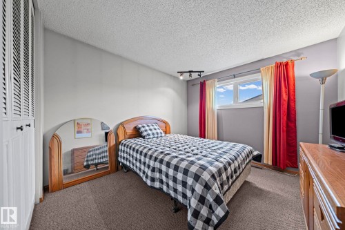 Built-in closet with louvered doors, light gray wall finishes, and a single window with a track light fixture - 17908 92A Street Nw, Edmonton, AB - Indoor Photo Showing Bedroom