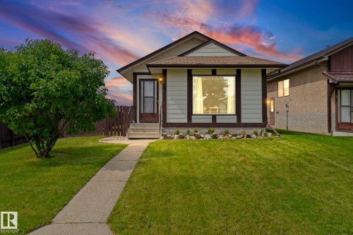 Front exterior featuring horizontal siding, a prominent front window with dark trim, a concrete walkway, and a manicured lawn - 17908 92A Street Nw, Edmonton, AB - Outdoor