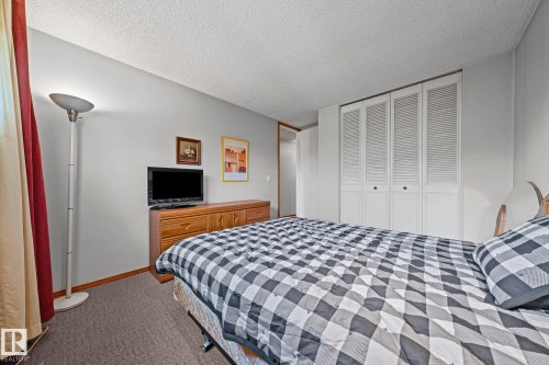 White louvered bi-fold closet doors, textured ceiling, and neutral wall color - 17908 92A Street Nw, Edmonton, AB - Indoor Photo Showing Bedroom