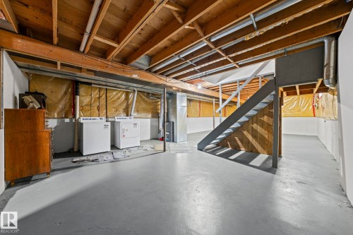Unfinished basement with exposed ceiling joists, concrete flooring, and a dedicated laundry area - 17908 92A Street Nw, Edmonton, AB - Indoor Photo Showing Basement