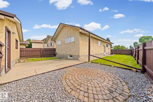 Paved driveway, gravel landscaping, a circular paver patio, a fenced yard, and a stucco exterior - 17908 92A Street Nw, Edmonton, AB - Outdoor With Exterior