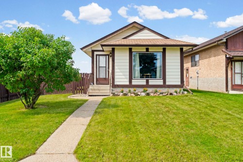 Light-toned siding with dark trim accents, bay window feature, concrete walkway, established front yard tree, and fenced perimeter - 17908 92A Street Nw, Edmonton, AB - Outdoor