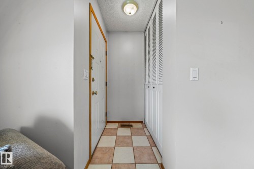 Entryway featuring a paneled door with wood trim, checkered tile flooring, and louvered bi-fold closet doors - 17908 92A Street Nw, Edmonton, AB - Indoor Photo Showing Other Room