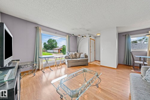 Wood-finish flooring throughout, complemented by a large picture window, and a white entry door - 17908 92A Street Nw, Edmonton, AB - Indoor Photo Showing Living Room