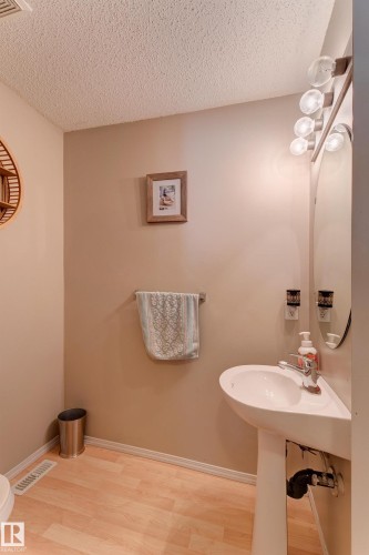 Pedestal sink with chrome faucet, light wood-finish flooring, and wall-mounted light fixture - 6218 1A Avenue Sw, Edmonton, AB - Indoor Photo Showing Bathroom