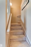Carpeted staircase with painted handrails and wall-mounted lighting - 