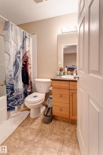 Bathroom featuring a vanity with wood-finish cabinetry, a large mirror, and a white bathtub with a shower - 6218 1A Avenue Sw, Edmonton, AB - Indoor Photo Showing Bathroom