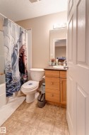 Bathroom featuring a vanity with wood-finish cabinetry, a large mirror, and a white bathtub with a shower - 