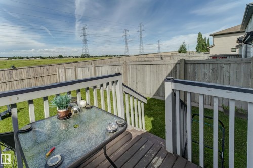 Elevated wood-finish deck with white railings and steps down to a green lawn - 6218 1A Avenue Sw, Edmonton, AB - Outdoor With Deck Patio Veranda