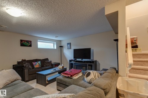 Recessed window with blinds, wall-mounted lighting fixture, carpeted flooring, and carpeted stairs with a white handrail - 6218 1A Avenue Sw, Edmonton, AB - Indoor