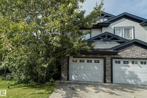 Exterior featuring horizontal siding, stone facade accents, multiple gabled rooflines with decorative trusses, and attached garages with window inserts - 6218 1A Avenue Sw, Edmonton, AB - Outdoor