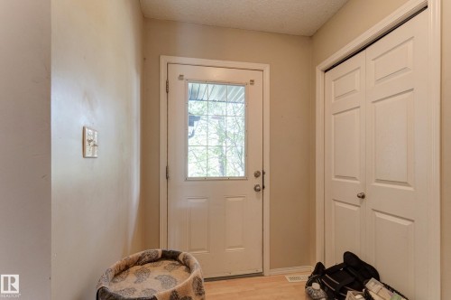 White entry door with decorative glass insert, paneled bifold closet doors, and wood-finish flooring - 6218 1A Avenue Sw, Edmonton, AB - Indoor Photo Showing Other Room