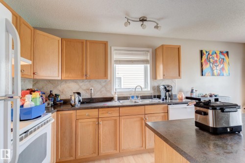 Kitchen featuring light wood cabinetry, a tiled backsplash, and a double basin sink - 6218 1A Avenue Sw, Edmonton, AB - Indoor Photo Showing Kitchen With Double Sink