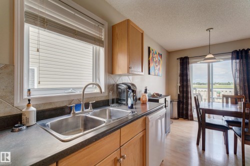 Kitchen featuring wood-finish cabinetry, a double basin stainless steel sink, and a tiled backsplash - 6218 1A Avenue Sw, Edmonton, AB - Indoor Photo Showing Kitchen With Double Sink