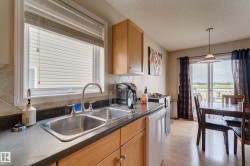 Kitchen featuring wood-finish cabinetry, a double basin stainless steel sink, and a tiled backsplash - 