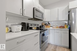 White shaker-style cabinetry, stainless steel appliances, light-toned countertops, and subway tile backsplash - 