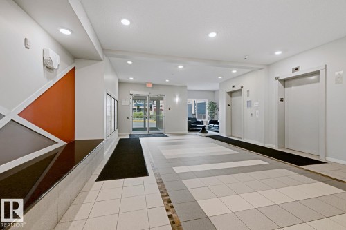 Common area with ceramic tile flooring, recessed lighting, and two elevators - #147 1818 Rutherford Rd Sw, Edmonton, AB - Indoor Photo Showing Other Room
