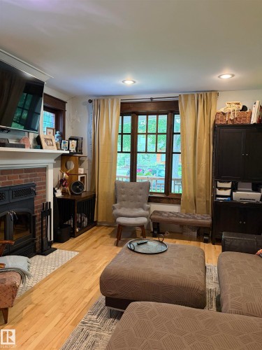 Brick fireplace with a black wood-burning insert and white mantel - 10994 126 St Nw Nw, Edmonton, AB - Indoor Photo Showing Living Room With Fireplace