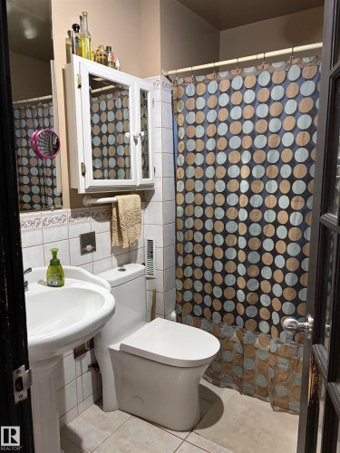 Pedestal sink, wall-mounted medicine cabinet, white tile wainscoting, and full-flush toilet - 10994 126 St Nw Nw, Edmonton, AB - Indoor Photo Showing Bathroom