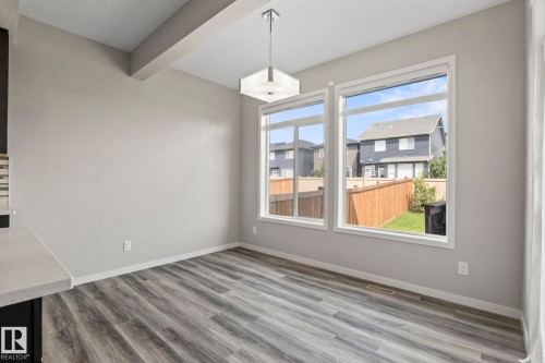 Wood-finish flooring, white trim, and a modern ceiling light fixture - 5210 23 Ave Sw, Edmonton, AB - Indoor Photo Showing Other Room