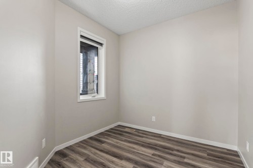 Neutral wall paint, wood-finish flooring, and a single window with white trim - 5210 23 Ave Sw, Edmonton, AB - Indoor Photo Showing Other Room