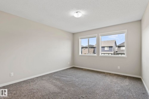 Neutral tone walls, ceiling-mounted light fixture, and textured carpeting - 5210 23 Ave Sw, Edmonton, AB - Indoor Photo Showing Other Room