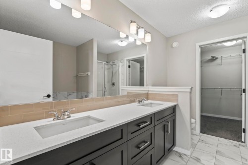 Dual vanity with integral sinks, white countertop, dark wood-finish cabinetry, and subway tile backsplash - 5210 23 Ave Sw, Edmonton, AB - Indoor Photo Showing Bathroom