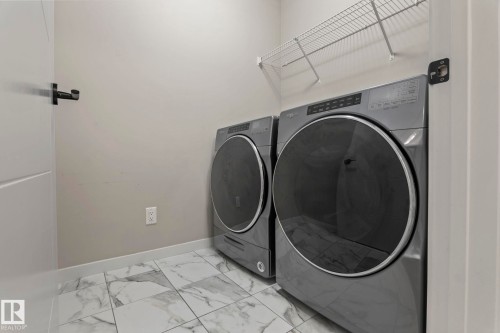 Laundry area featuring tile flooring, white walls, and a wire storage shelf - 5210 23 Ave Sw, Edmonton, AB - Indoor Photo Showing Laundry Room