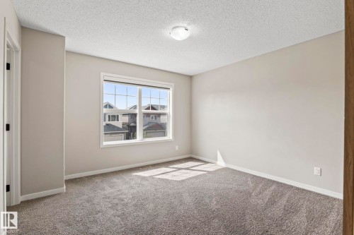 Neutral tone walls, textured ceiling, flush mount lighting, framed window, and gray carpet - 5210 23 Ave Sw, Edmonton, AB - Indoor Photo Showing Other Room