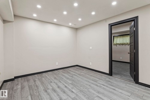 Recessed lighting, light gray walls, wood-finish flooring, dark trim, and dark interior door - 5210 23 Ave Sw, Edmonton, AB - Indoor Photo Showing Other Room
