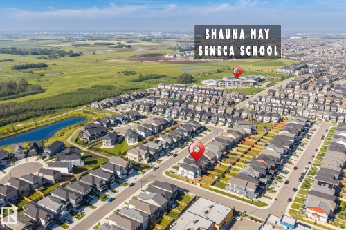 Aerial perspective showcasing a residential development with extensive green space, a water feature, and a school building - 5210 23 Ave Sw, Edmonton, AB - Outdoor With View