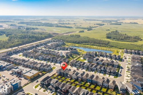 Aerial perspective of a developed residential area with a prominent central pond, surrounded by green spaces and agricultural land - 5210 23 Ave Sw, Edmonton, AB - Outdoor With View
