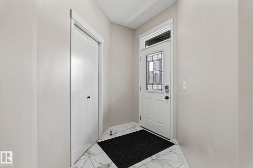 Entryway featuring decorative glass door, transom window, bifold closet, and white-patterned tile flooring - 5210 23 Ave Sw, Edmonton, AB - Indoor Photo Showing Other Room