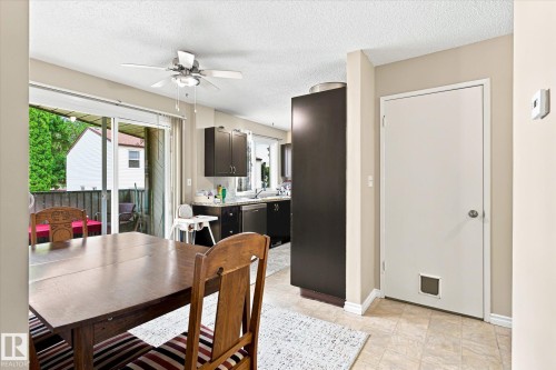 Dining area with a wood-finish table, ceiling fan, and sliding glass door leading to an outdoor space - 6471 180 Street Nw, Edmonton, AB - Indoor Photo Showing Dining Room