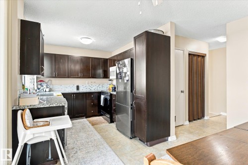 Kitchen featuring dark wood-finish cabinetry, light-toned countertops, and a patterned tile backsplash - 6471 180 Street Nw, Edmonton, AB - Indoor Photo Showing Kitchen