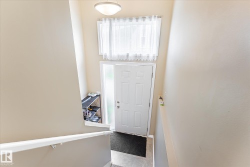 Entryway with a white door, frosted glass sidelight, and an overhead window with sheer privacy curtains - 6471 180 Street Nw, Edmonton, AB - Indoor Photo Showing Other Room