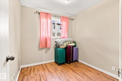 Wood-finish flooring with white trim, neutral wall color, and a window with a curtain rod - 6471 180 Street Nw, Edmonton, AB - Indoor Photo Showing Other Room