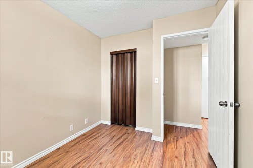 Wood-finish flooring, neutral-toned walls, and a wood-finish accordion door - 6471 180 Street Nw, Edmonton, AB - Indoor Photo Showing Other Room