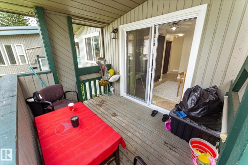 Outdoor balcony featuring wood-finish decking, vertical panel siding, and a sliding glass door - 6471 180 Street Nw, Edmonton, AB - Outdoor With Deck Patio Veranda With Exterior