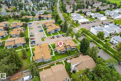 Aerial perspective showcasing residential neighborhood with mature trees, paved streets, and multiple parking areas - 6471 180 Street Nw, Edmonton, AB - Outdoor With View