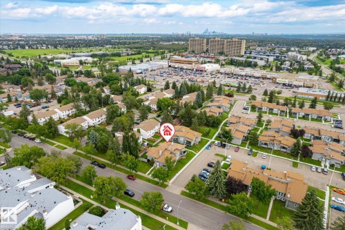 Aerial perspective showcasing a residential community with mature landscaping, multiple parking areas, and nearby commercial establishments - 6471 180 Street Nw, Edmonton, AB - Outdoor With View