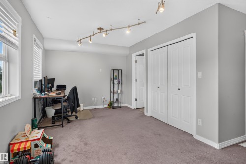 Recessed window with blinds, dual bi-fold closet doors, track lighting fixture, and carpeted flooring - 4471 Mccrae Avenue Nw, Edmonton, AB - Indoor Photo Showing Office