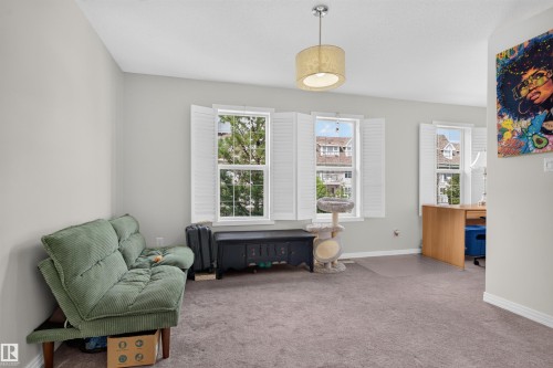 Carpeted interior with light gray walls, multiple windows with white plantation shutters, and a drum pendant light fixture - 4471 Mccrae Avenue Nw, Edmonton, AB - Indoor