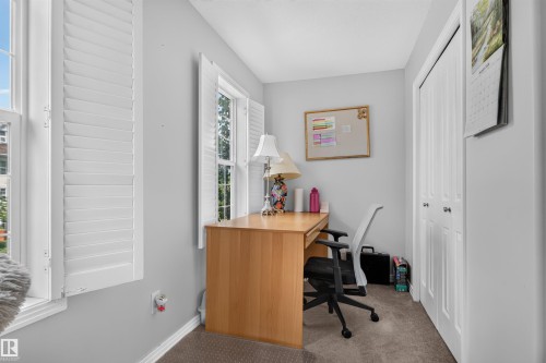 Two double-hung windows with plantation shutters, neutral wall color, and a bi-fold closet door - 4471 Mccrae Avenue Nw, Edmonton, AB - Indoor Photo Showing Office